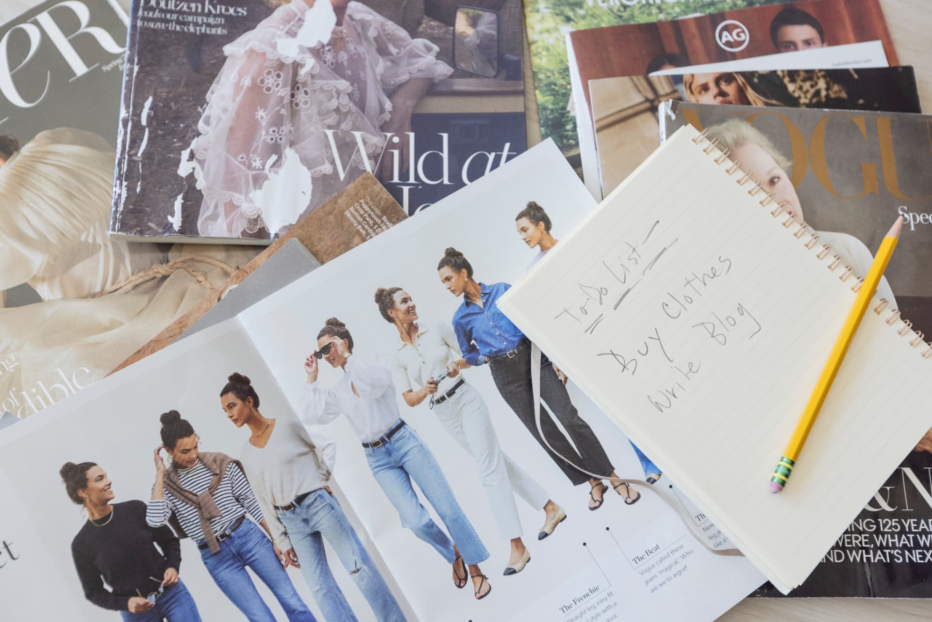 Fashion magazines and a styling notebook spread out for inspiration